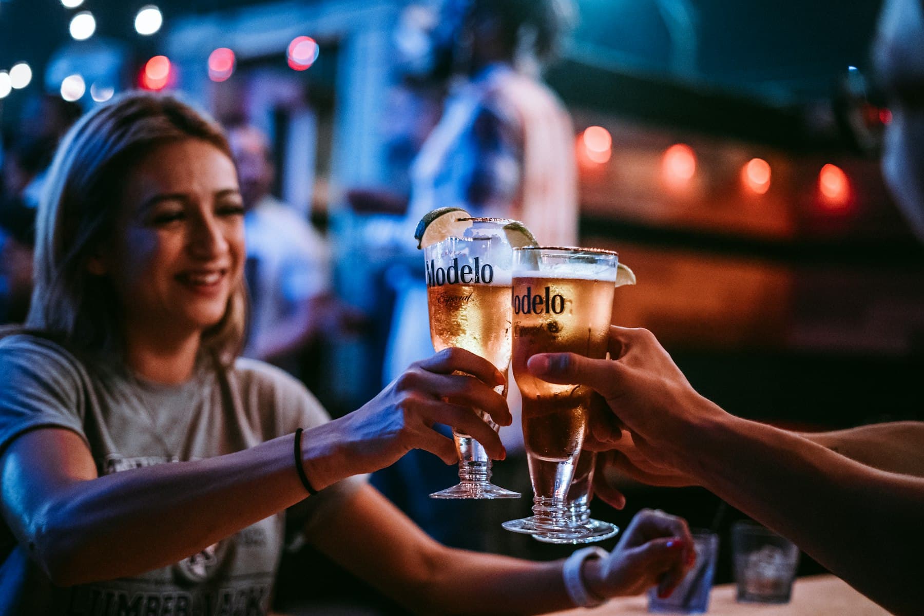 Des clients trinquent, verres levés, dans un bar en soirée.