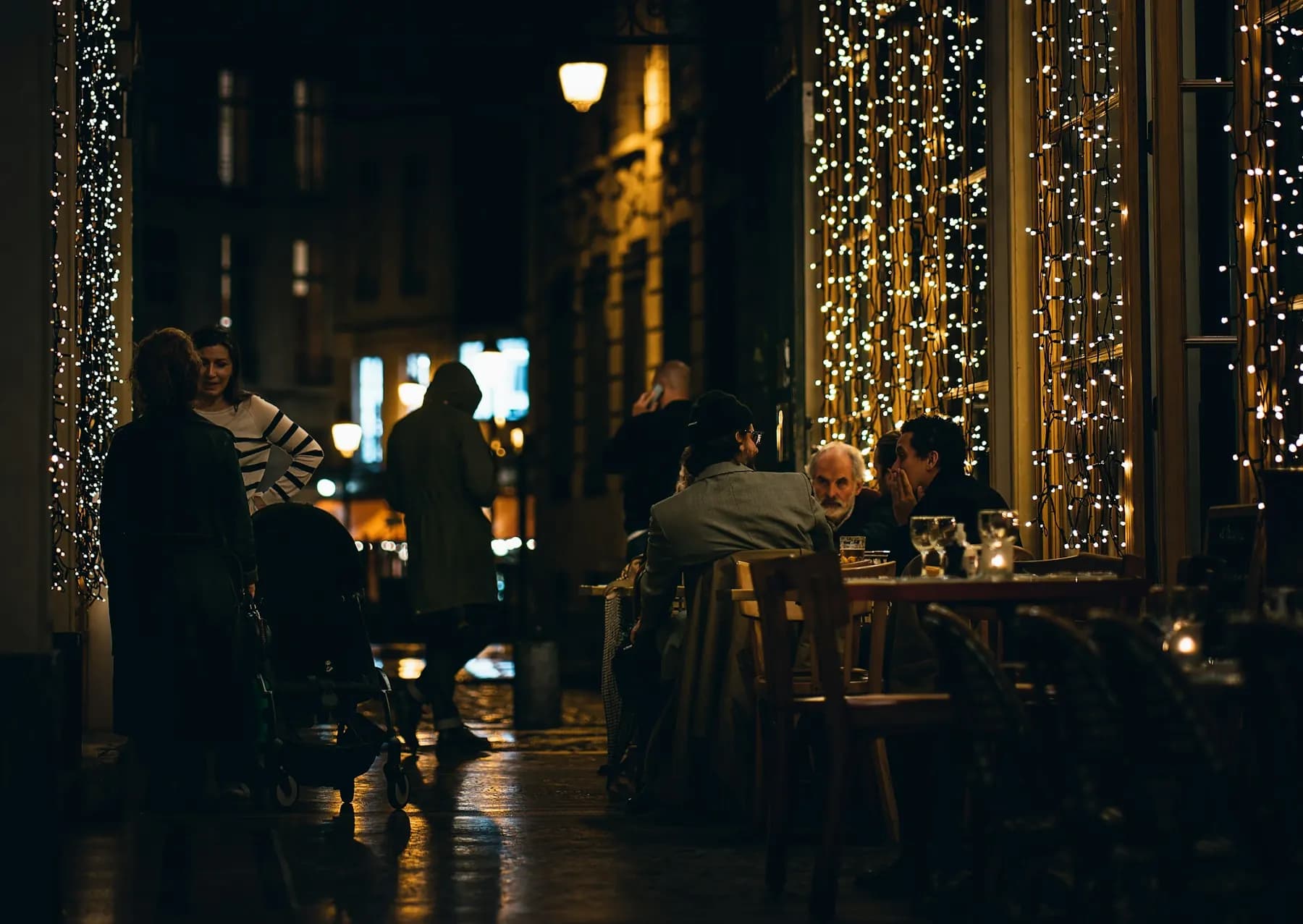 Le soir, une terrasse sous des guirlandes lumineuses : des clients attablés, d’autres qui passent dans la rue.