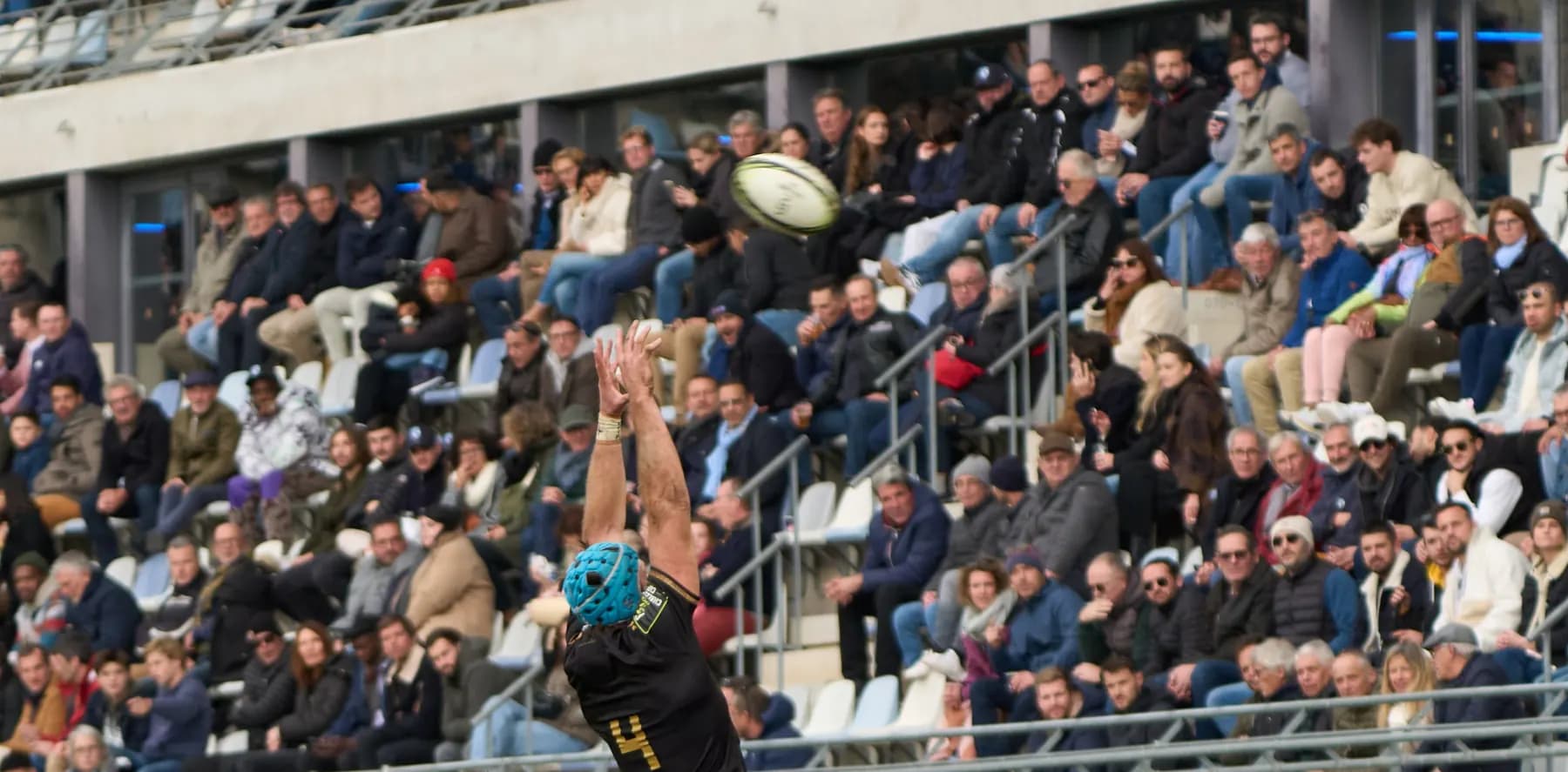 En touche, un sauteur s’élève vers le ballon devant une tribune pleine de spectateurs.